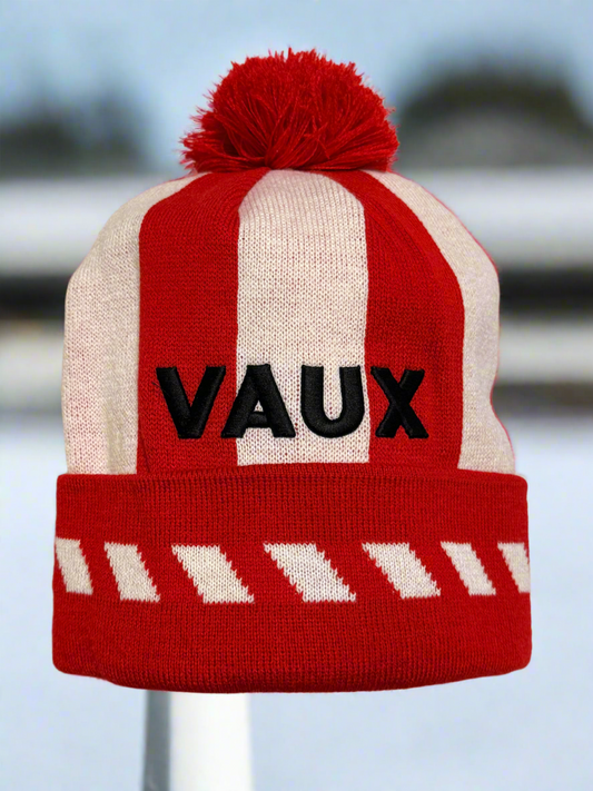 Red and white striped beanie with 'VAUX' branding on a blurred background