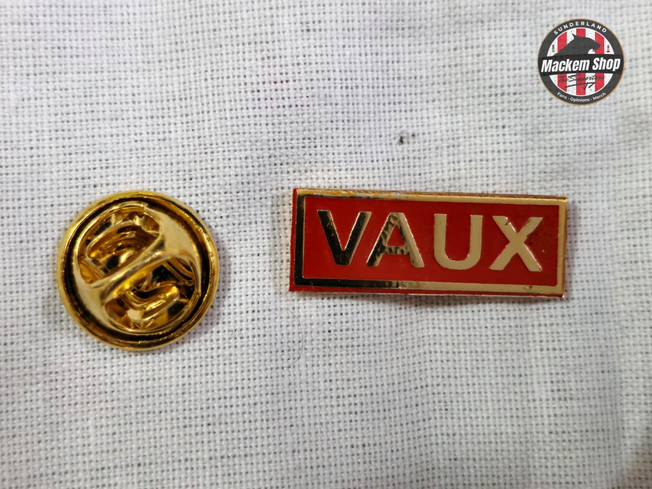 Red and gold 'VAUX' badge on a textured white background