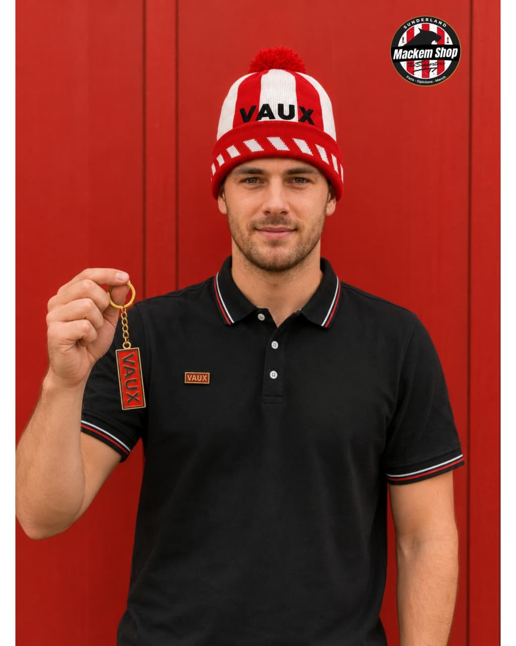 A man wearing a red and white striped Vaux knit beanie with a red pom-pom and a black polo shirt with red and white trim, holding a small red Vaux tag against a red paneled background. A circular 'Mackem Shop' logo is visible in the top right corner.