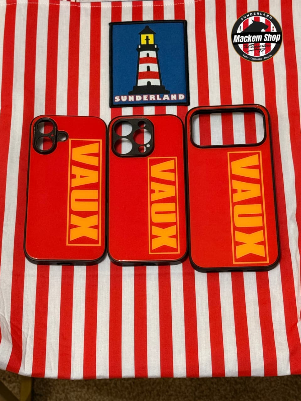 Three red phone cases with 'VAUX' branding on a red and white striped background.