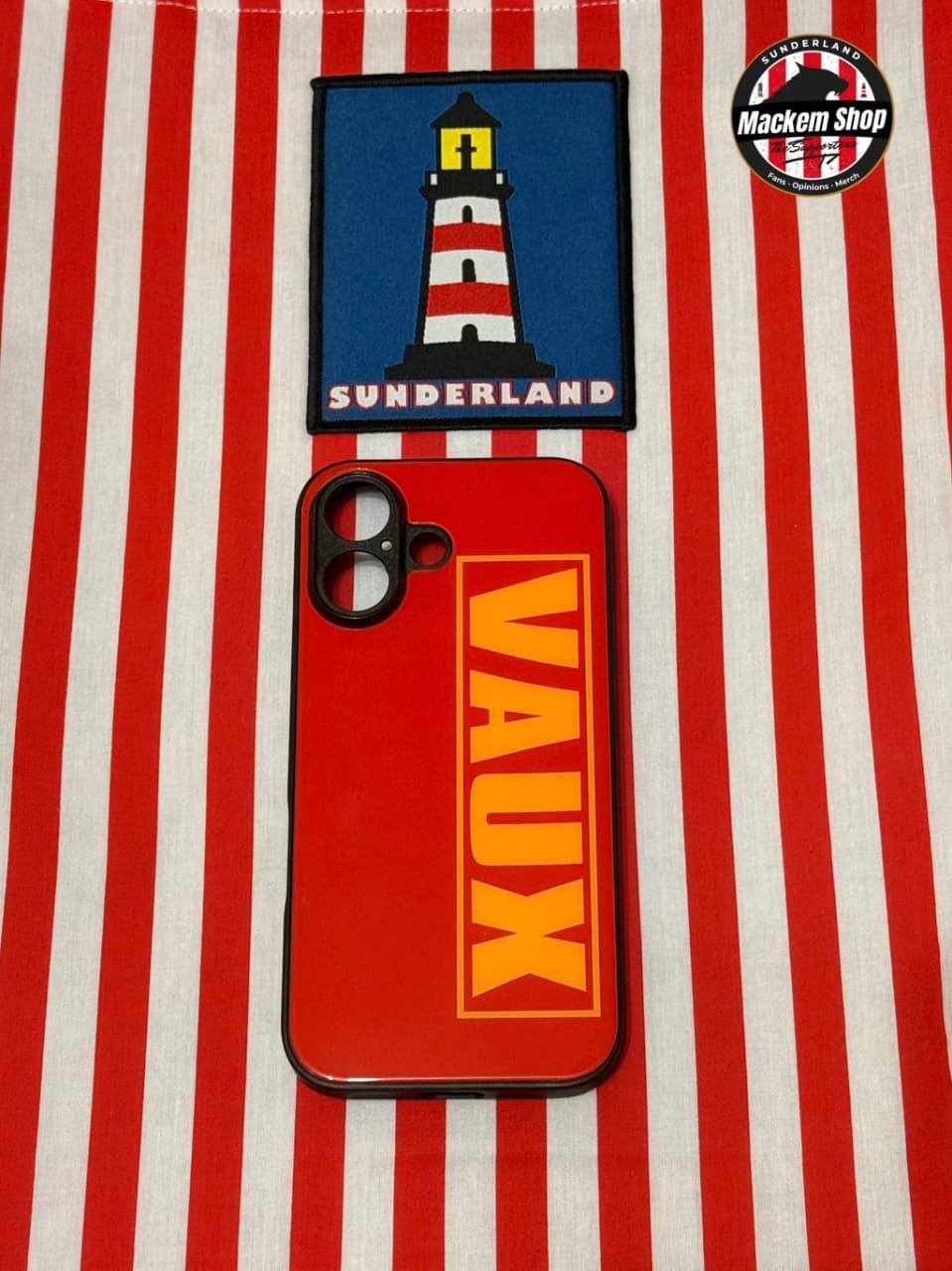 Phone case with 'VAUX' branding and a Sunderland lighthouse patch on a red and white striped background.