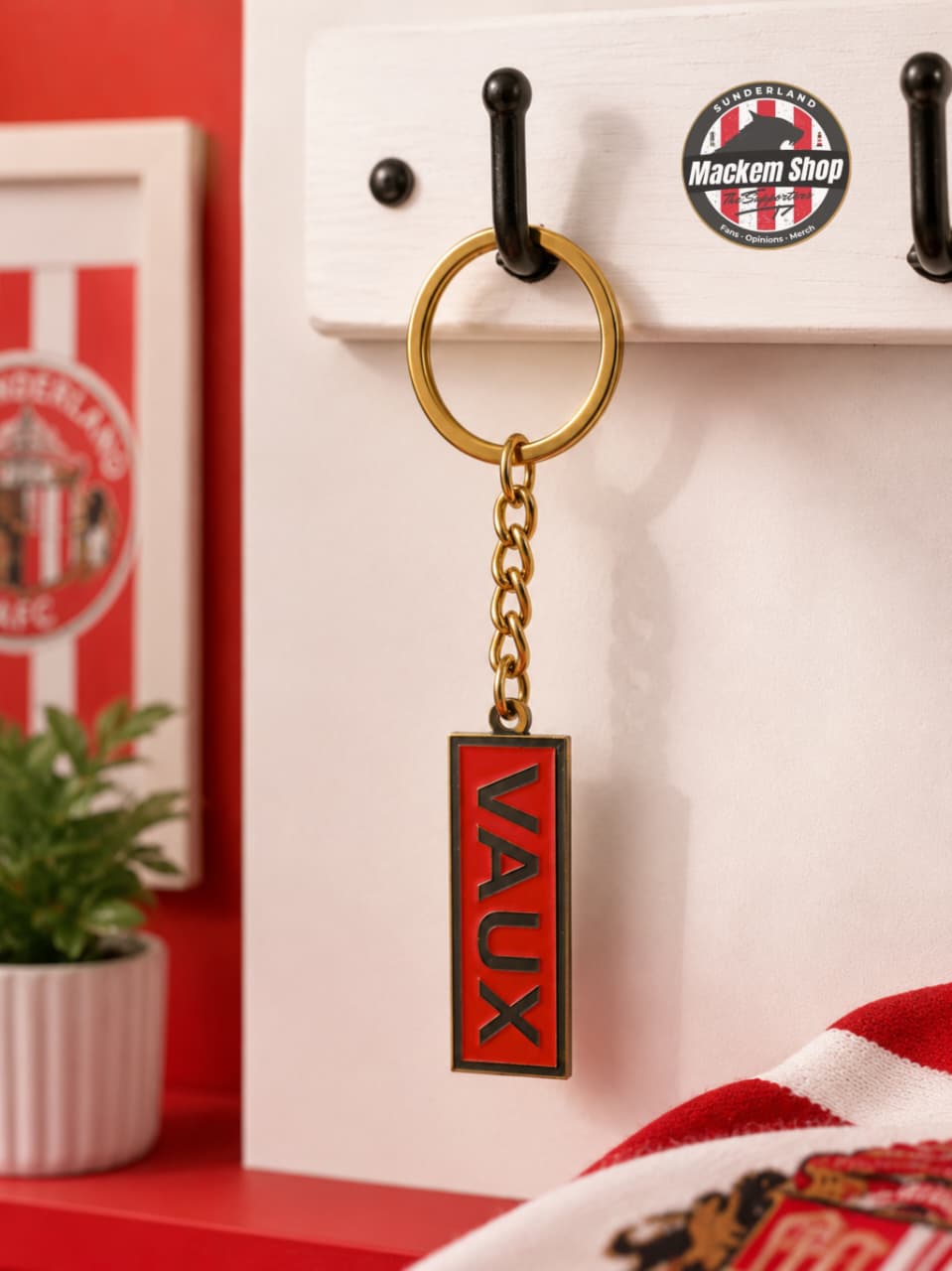Keychain with 'VAUX' on a hook against a red and white background