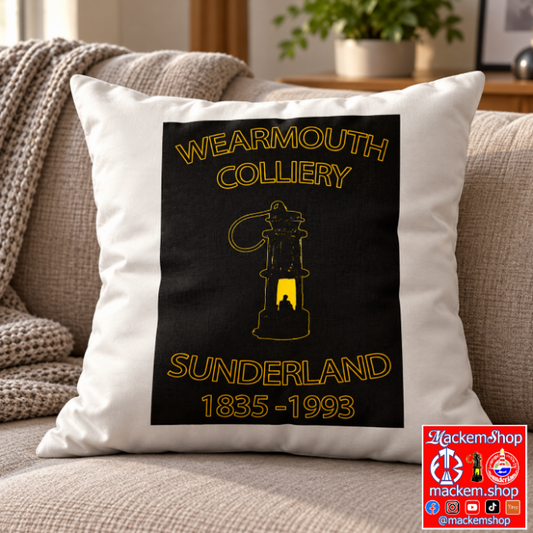 A square white throw pillow with a black graphic print featuring the text 'WEARMOUTH COLLIERY' and 'SUNDERLAND 1835-1993' in yellow, styled on a beige sofa in a living room setting, with MackemShop logo overlay in right bottom corner.
