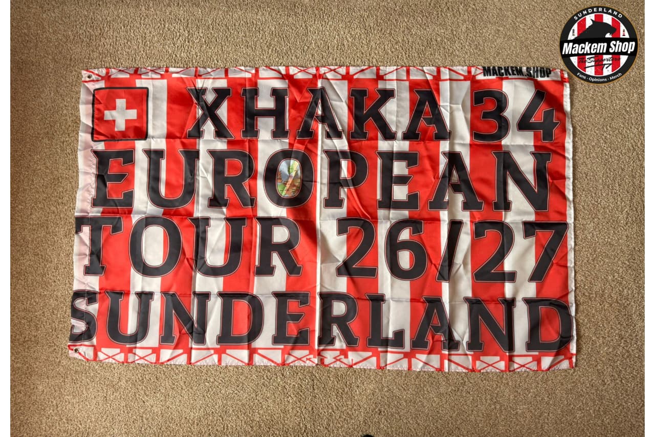 Flag with text 'Xhaka 34 European Tour 26/27 Sunderland' on a red and white striped background.