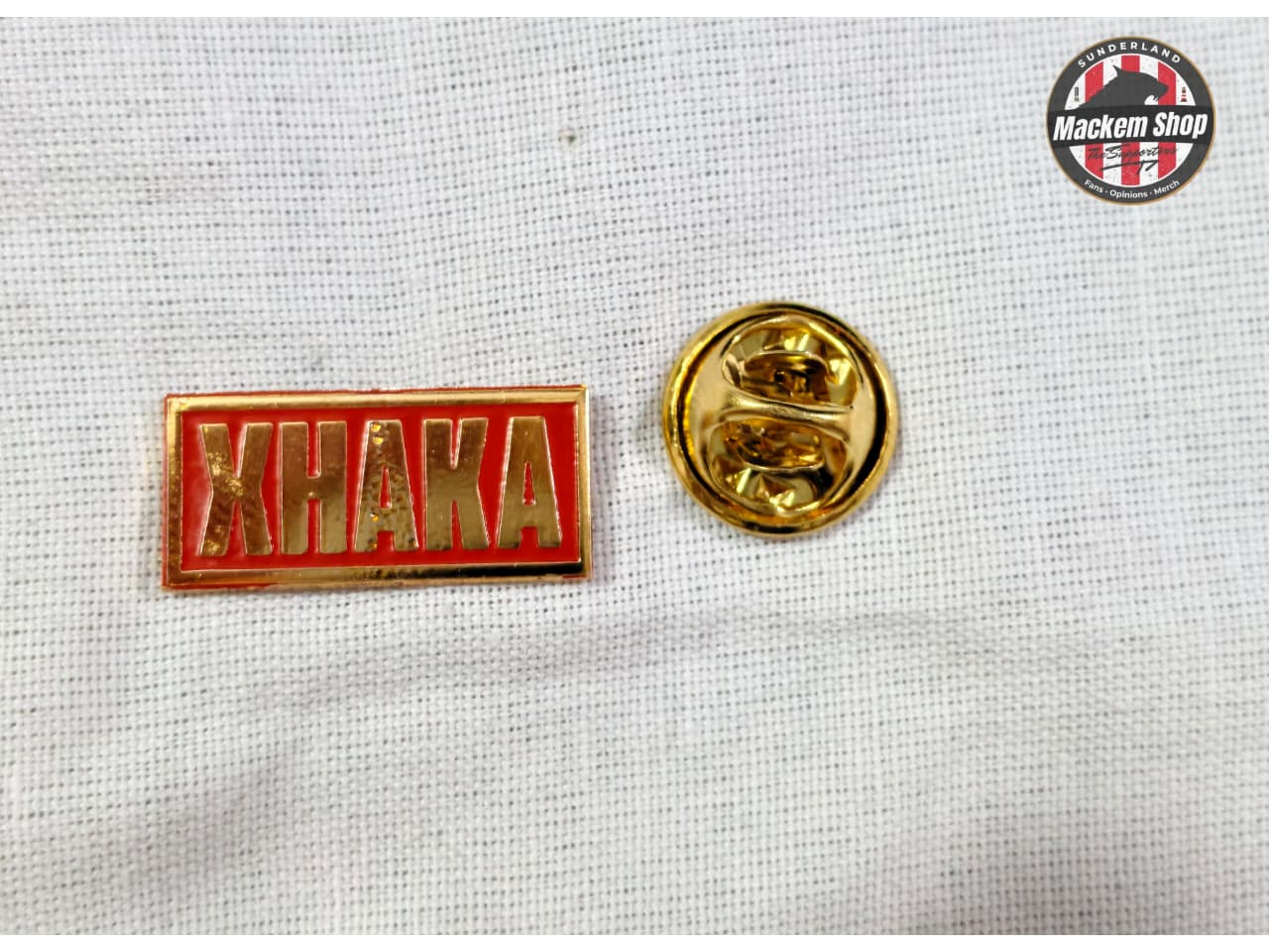 Yellow and red 'KHAKA' lapel pin on a textured white background with 'MackemShop' logo.