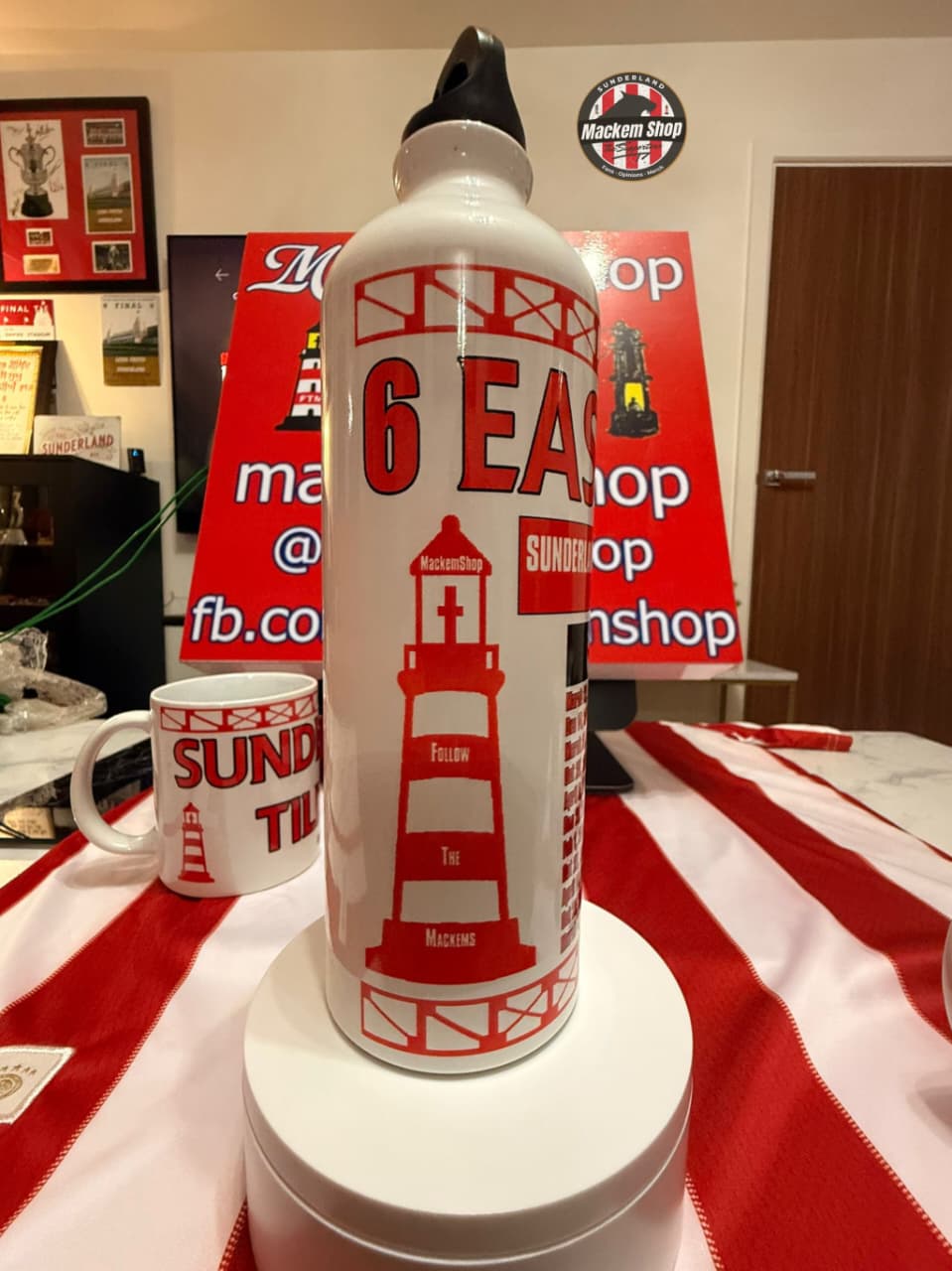 White water bottle with red lighthouse design on a table with a red and white striped cloth.