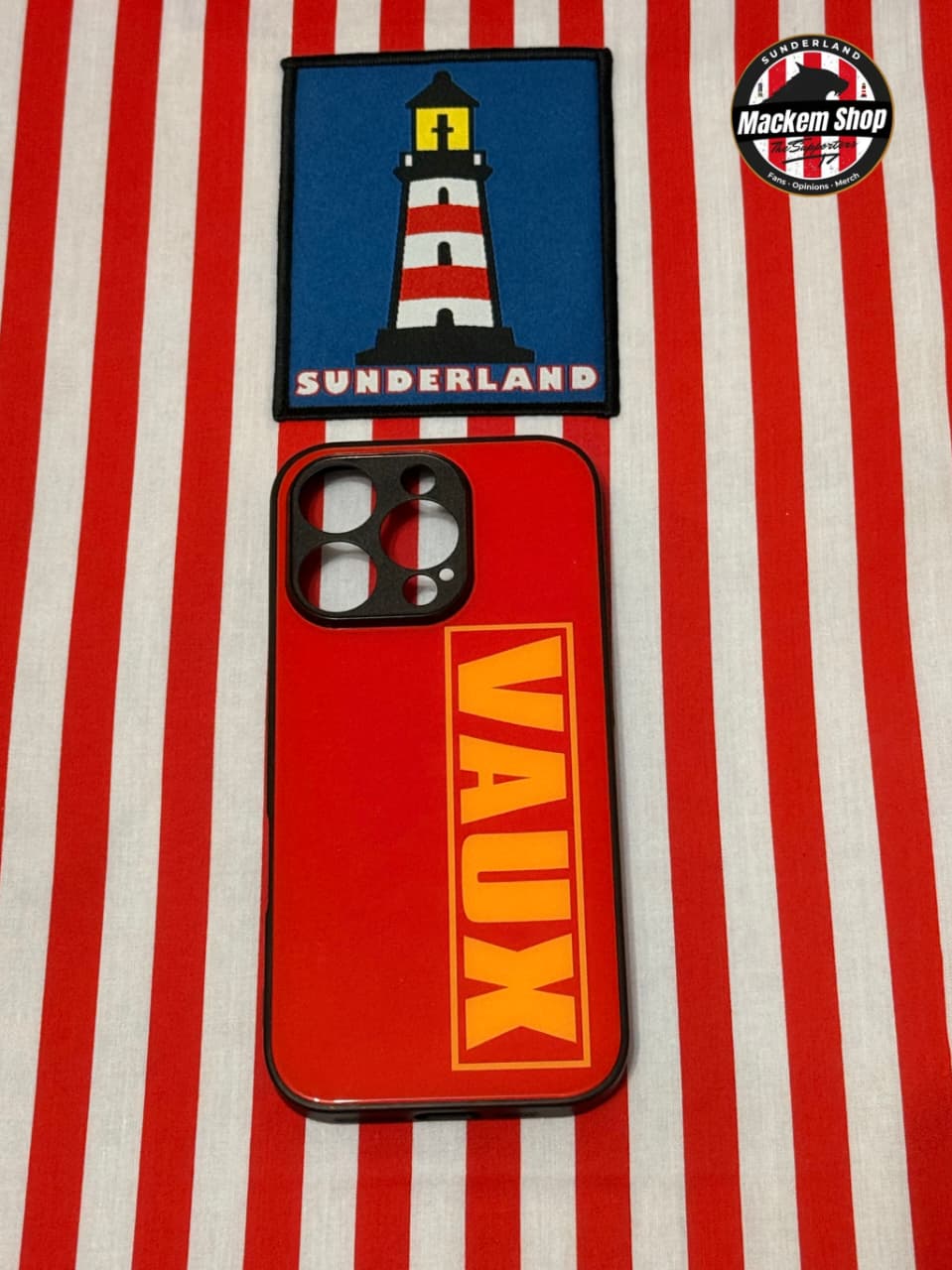 Phone case with lighthouse design and 'VAUX' branding on a red and white striped background.