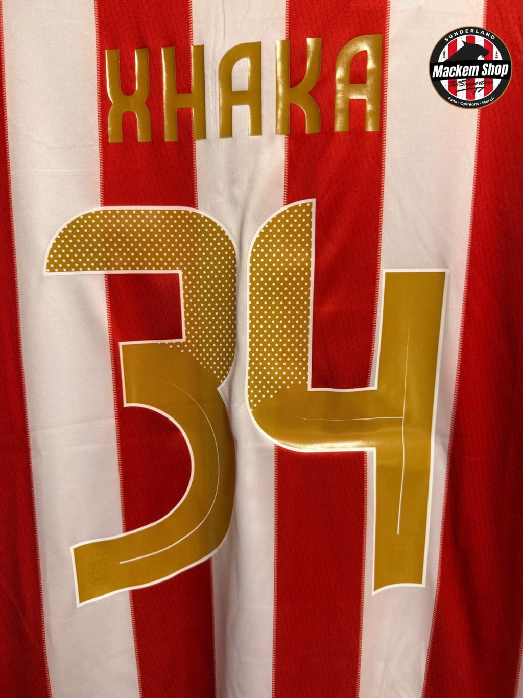 Red and white striped jersey with XHAKA text and number 34, featuring a logo in the corner.